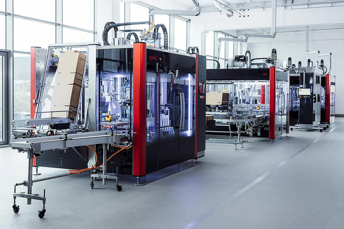Multiple SOMIC packaging machines lined up during commissioning in a modern production facility